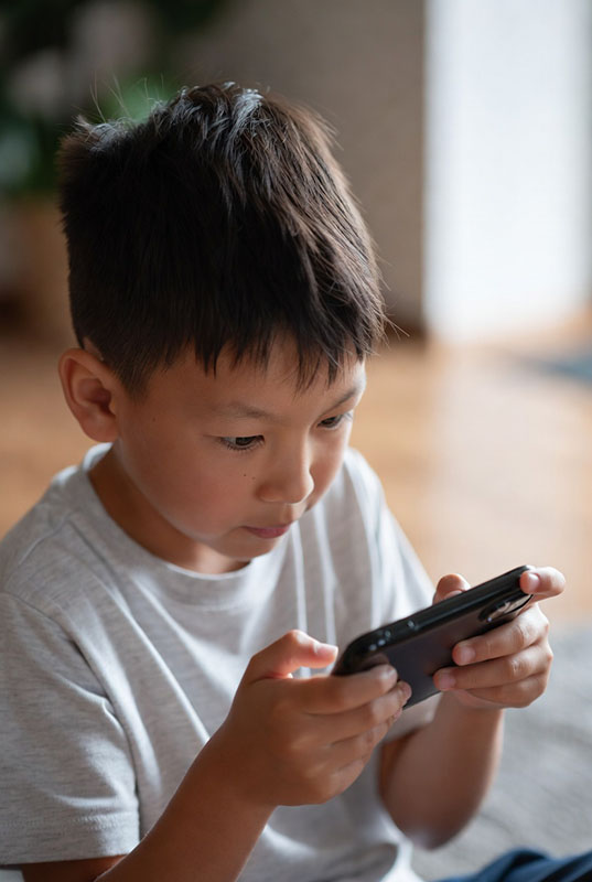 پسر بچه ای که با تلفن همراه مشغول بازی است